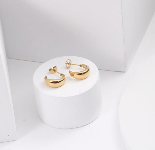 A pair of 3Souls Company Huggie Earrings sitting on top of a white table.
