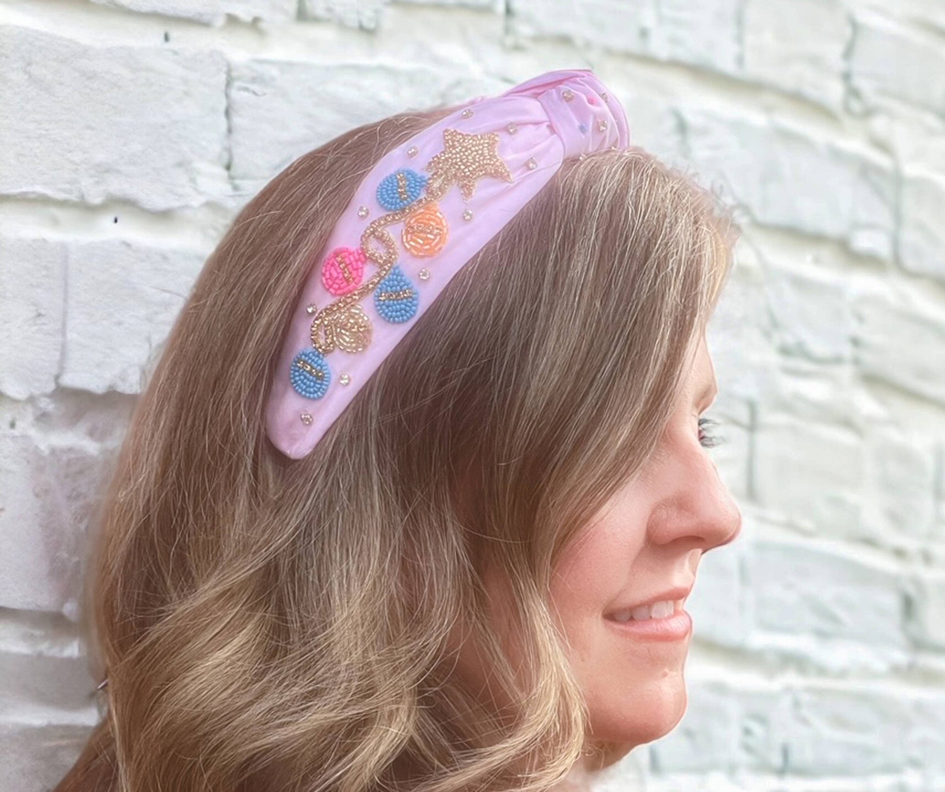 A woman wearing a Bash Beaded Pink Christmas Lights Headband - Festive Holiday Accessories with beaded stars on it.