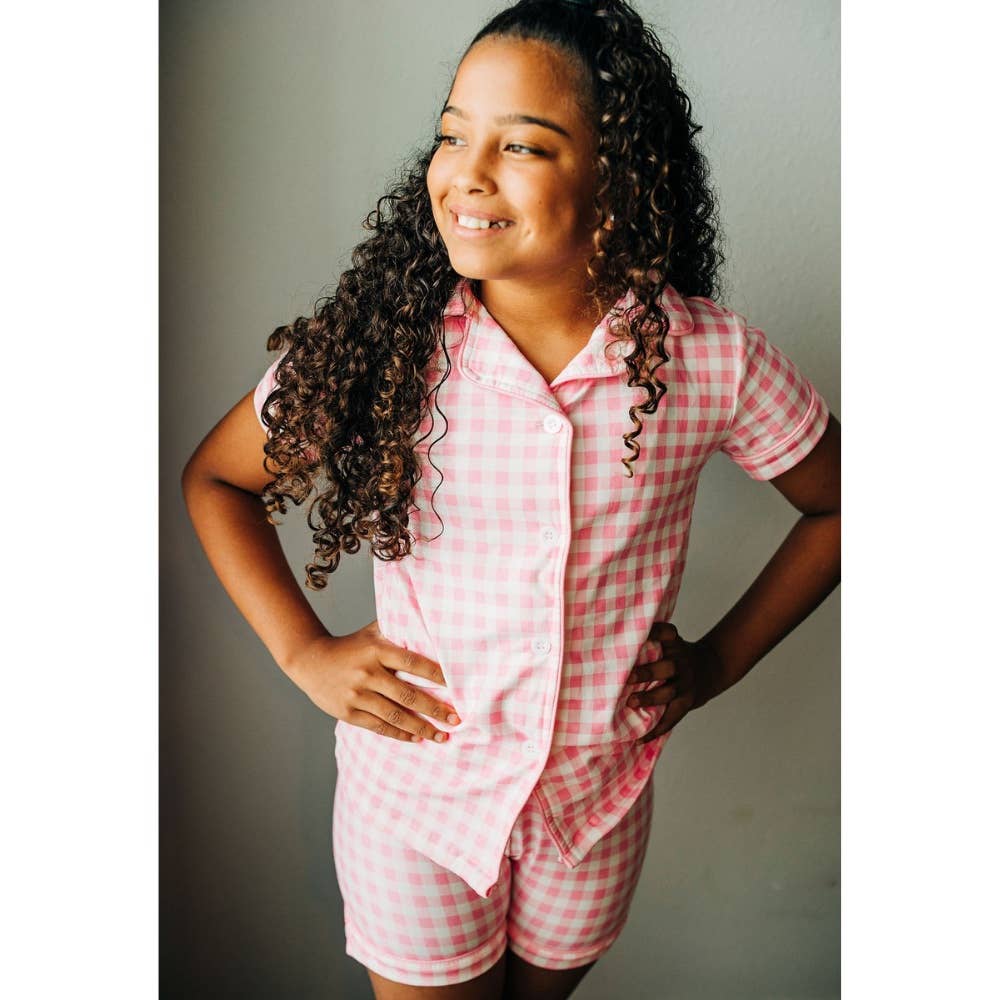 A young girl wearing Sugar Bee Clothing's Pink Gingham Button Down Pajamas.
