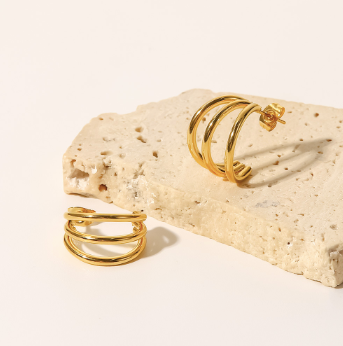 A pair of Triple Hug Earrings from 3Souls Company sitting on top of a rock.