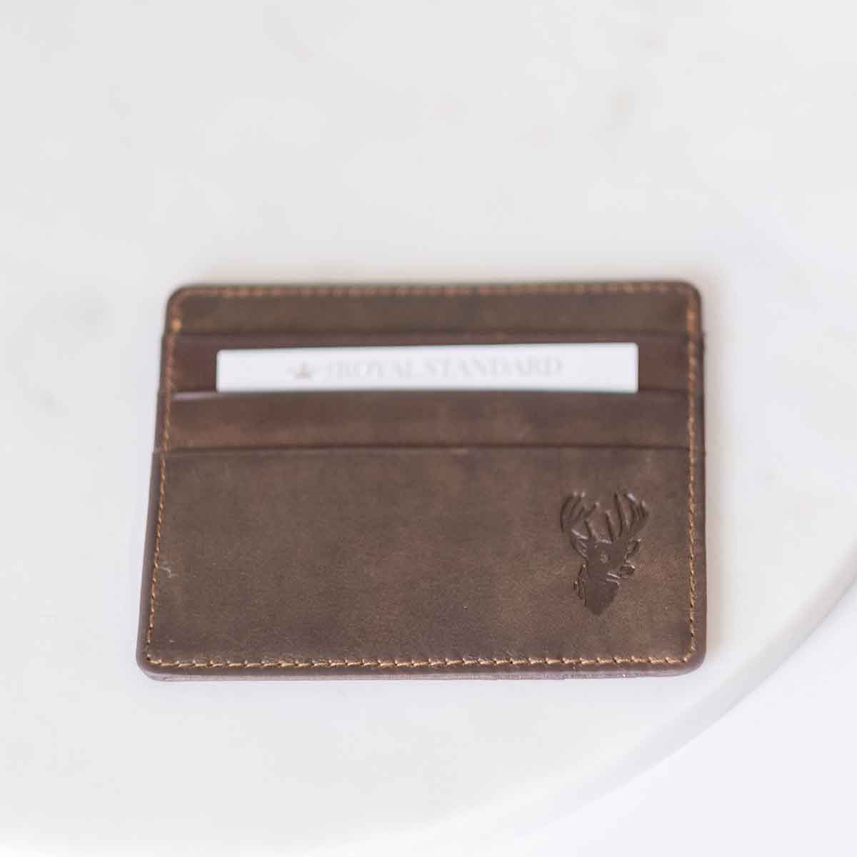 A Deer Leather Embossed Slim Wallet by The Royal Standard in dark brown with a deer head on it.